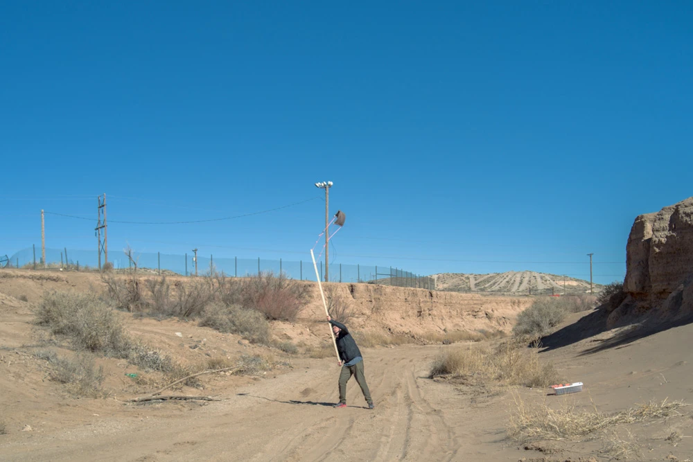 Using a stick sling to attempt to throw dust into the air